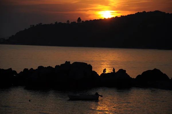 在海上落日和人物形象的轮廓 一对夫妇在美丽的海滩上欣赏日落 — 图库照片