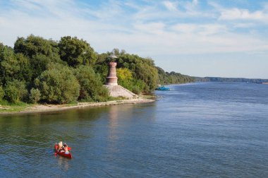 Lighthouse on confluence of the River Tamis and Danube. Two young women in canoe. clipart