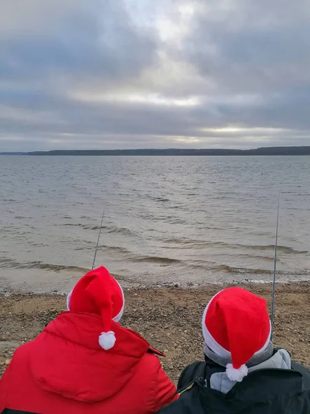 Weihnachtsmann claus angelt mit seiner angelrute nach weihnachtsgeschenken. Der Weihnachtsmann fängt beim Fischen ein Geschenk. — Stockfoto