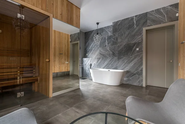Роскошная ванная комната с белоснежной ванной против мраморной стены при естественном освещении — стоковое фото