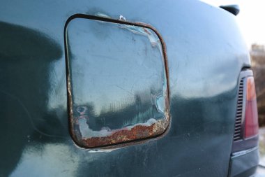 Araba tankının kapağında aşınma ve pas var. Araba tamiri ya da boyama ihtiyacı kavramı.