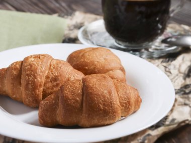 Beyaz tabakta kruvasanlar ve yakın plan tahta masa. Mükemmel lezzetli kahvaltı ya da öğle yemeği konsepti.