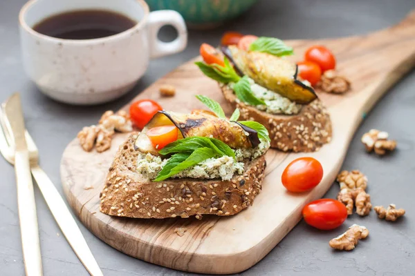Krem peynirli çavdar ekmeği, sarımsak ve fesleğen sosu, kiraz domatesleri, taze nane, fındık ve ahşap tahtada ızgara patlıcan.