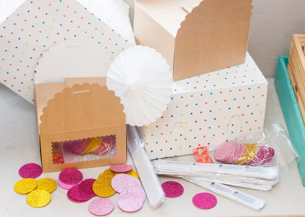 Crafted paper gift boxes with confetti, garland and wafer paper decoration on grey background.