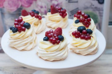 Krem peynirli mini pavlova kekleri ve taze böğürtlen, yabanmersini, ahududu ve çilek beyaz pasta standında.. 