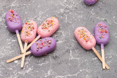 Gri mermer arka planda pembe ve mor çikolata kaplı buzlu şekerler.