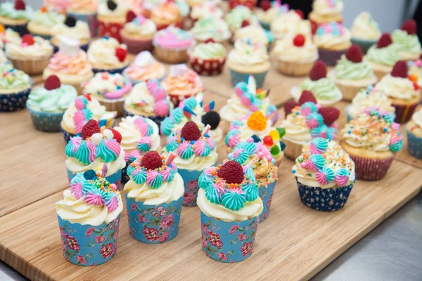 Mavi, pembe ve turuncu kremalı çeşitli renkli kekler, ahududu, şekerleme ve şekerle süslenmiş.. 