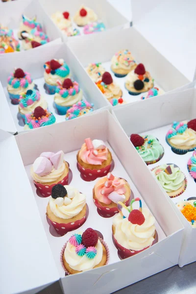 Mavi, pembe ve turuncu kremalı çeşitli renkli kekler, ahududu, şekerleme ve şekerle süslenmiş.. 