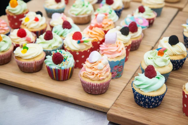 Mavi, pembe ve turuncu kremalı çeşitli renkli kekler, ahududu, şekerleme ve şekerle süslenmiş.. 