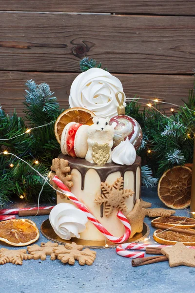 New Year cake with chocolate mouse, meringue, macaroons, candy cane, gingerbread cookies and dried oranges.