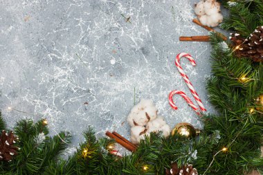 Gri arkaplan Noel ağacı çelengi, sicim ışıkları, çam ağaçları, baston şekerler ve tarçın ruloları.