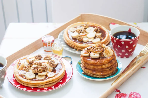 2杯のコーヒーとパンケーキ コーンシロップ バナナ 木のトレイのナッツ — ストック写真