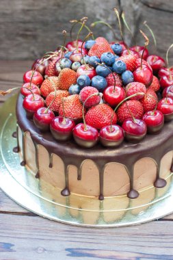 Erimiş siyah çikolata ve taze çilek ile çikolatalı pasta, üstünde yaban mersini ve kiraz..