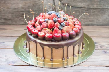 Erimiş siyah çikolata ve taze çilek ile çikolatalı pasta, üstünde yaban mersini ve kiraz..
