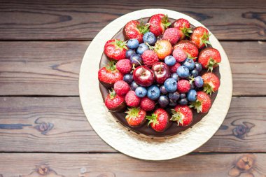 Taze çilekli çikolatalı pasta, yaban mersini, ahududu ve kirazlar ahşap arka planda.. 