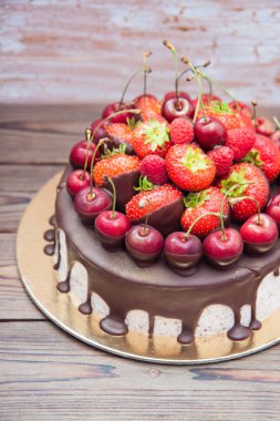 Erimiş çikolatalı cheesecake, taze çilek, kiraz ve ahududu ahşap arka planda.. 