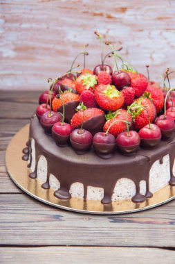 Erimiş çikolatalı cheesecake, taze çilek, kiraz ve ahududu ahşap arka planda.. 