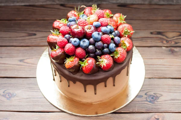 Erimiş çikolatalı kek, taze çilek, ahududu, yabanmersini ve kırsal kahverengi arka planda üzüm.. 