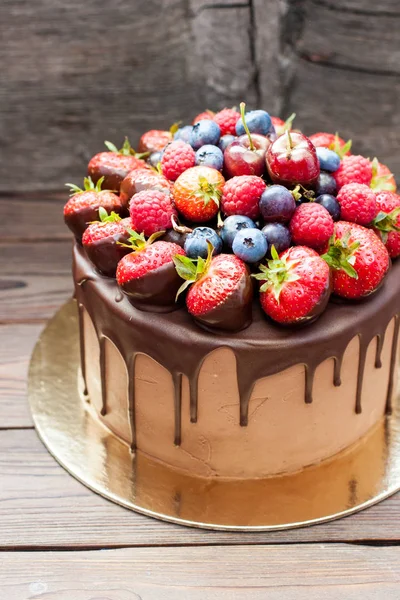 Erimiş çikolatalı kek, taze çilek, ahududu, yabanmersini ve kırsal kahverengi arka planda üzüm.. 
