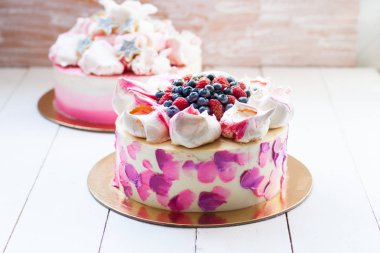 Beyaz, pembe, mor ve menekşe noktalı kek krema bulutları ve bir avuç taze ahududu, çilek, yabanmersini ve kiraz