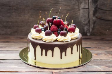 Vanilla cake with melted chocolate, swiss meringue frosting, fresh cherries, strawberries, raspberries, blueberries. 