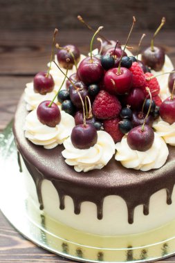 Vanilla cake with melted chocolate, swiss meringue frosting, fresh cherries, strawberries, raspberries, blueberries. 