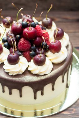 Vanilla cake with melted chocolate, swiss meringue frosting, fresh cherries, strawberries, raspberries, blueberries. 