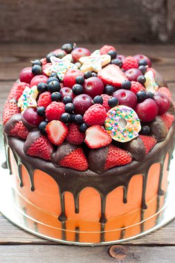 Orange cake with melted chocolate, fresh berries, strawberries, raspberries, blueberries, cherries and chocolate stars with sprinkles. 