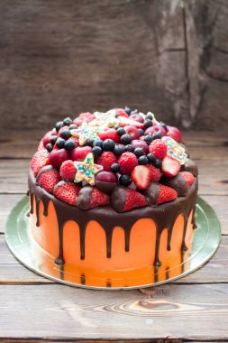 Orange cake with melted chocolate, fresh berries, strawberries, raspberries, blueberries, cherries and chocolate stars with sprinkles. 