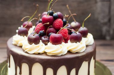 Vanilla cake with melted chocolate, swiss meringue frosting, fresh cherries, strawberries, raspberries, blueberries. 