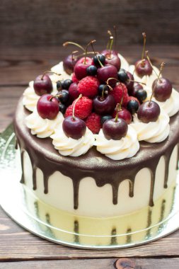 Vanilla cake with melted chocolate, swiss meringue frosting, fresh cherries, strawberries, raspberries, blueberries. 