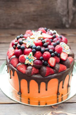 Orange cake with melted chocolate, fresh berries, strawberries, raspberries, blueberries, cherries and chocolate stars with sprinkles. 