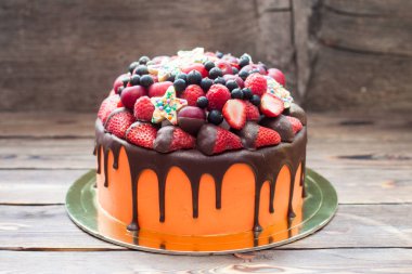 Orange cake with melted chocolate, fresh berries, strawberries, raspberries, blueberries, cherries and chocolate stars with sprinkles. 