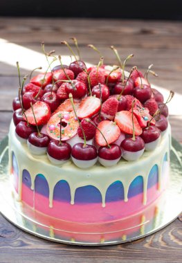 Erimiş çikolata, taze neşe, çilek, ahududu ve mini donutlu mavi, pembe ve menekşe çizgili pasta.