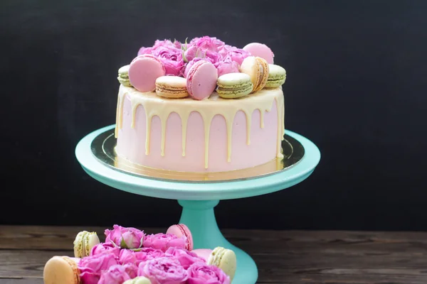 Pink, ivory and turquoise cake with melted white chocolate, fresh roses and french macaroons