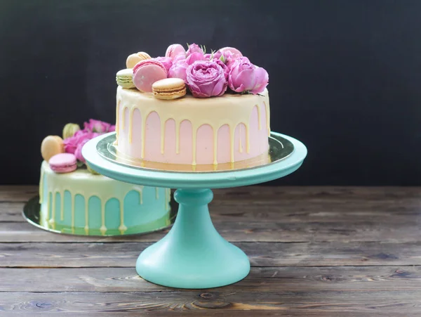 Pink, ivory and turquoise cake with melted white chocolate, fresh roses and french macaroons