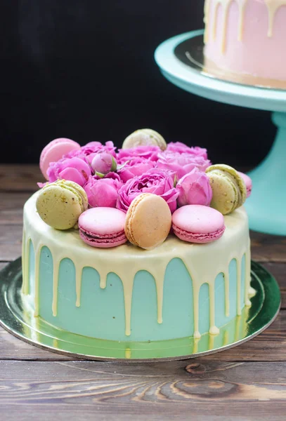 Turquoise cake with white melted chocolate, fresh roses and french macaroons decoration