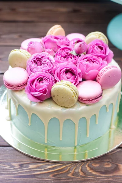 Turquoise cake with white melted chocolate, fresh roses and french macaroons decoration