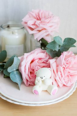 Bir tabakta beyaz çikolata ayısı ve arka planda mumlar.