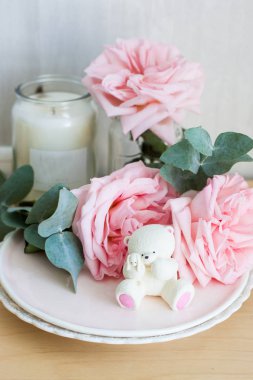 Bir tabakta beyaz çikolata ayısı ve arka planda mumlar.