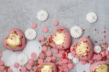 Çikolata damlaları, kremalar ve kurumuş meyvelerle sertleştirilmiş pembe kalpler.