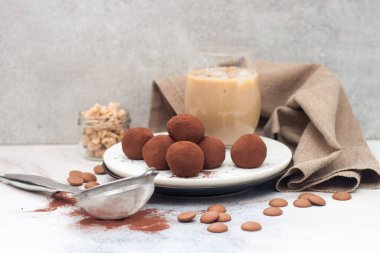 Çikolata mantarlı soğuk kahve likörü, gri arka planda kakao tozu.