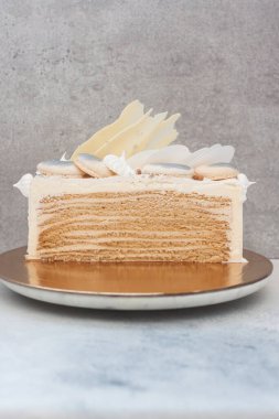 Çikolatayla süslenmiş, beyaz pasta üzerine katmanlı bal keki.