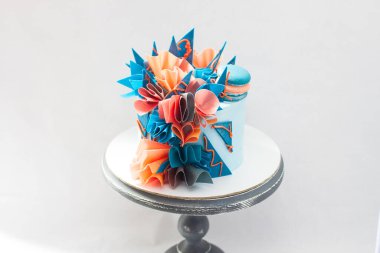 Gofret kağıdı, çikolata ve kurabiyeli modern mavi ve turuncu doğum günü pastası. Düz gri arkaplan. Boşluğu kopyala.