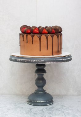 Erimiş çikolataya batırılmış çilekli çikolatalı kek. Gri mermer pasta, açık gri arka plan. Boşluğu kopyala.