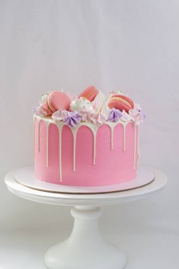 Erimiş beyaz çikolata, badem kurabiyesi, pasta çubuğu ve beyaz kek üzerine şekerle süslenmiş yumuşak pembe pasta. Düz arkaplan.