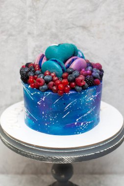 Taze böğürtlen, badem kurabiyesi ve şekerle süslenmiş kır pastası üzerine uzay mavisi pastası. Gri arkaplan