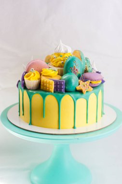 Yeşil eritilmiş çikolatalı parlak sarı pasta, kekler, kekler, çikolatalar ve donut süslemeleri. Düz arkaplan. Boşluğu kopyala.