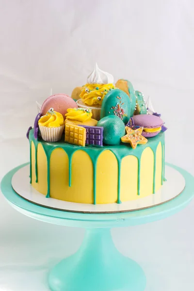 Yeşil eritilmiş çikolatalı parlak sarı pasta, kekler, kekler, çikolatalar ve donut süslemeleri. Düz arkaplan. Boşluğu kopyala.