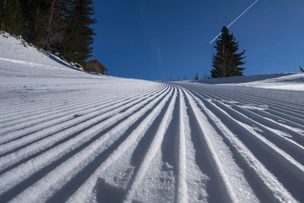 Kar kadifesi, karlı dağ zirvelerinin arka planındaki kayak yamacına yaklaş. Kar üzerinde kar temizleyicisi izi olan kayak ve snowboard pisti hazırlandı. İtalya, Cima Piazzi San Colombano. — Stok fotoğraf